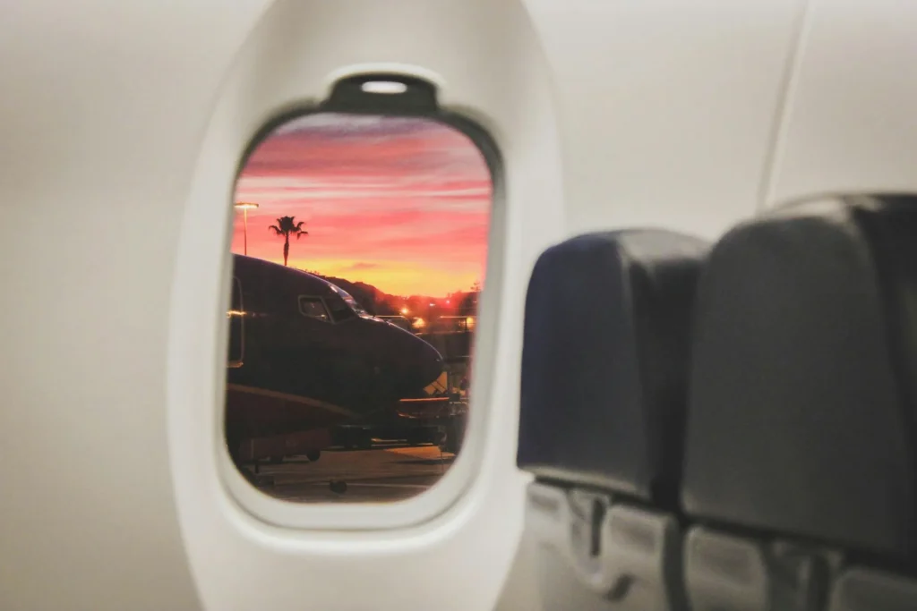 photo tropical landscape with pink evening sky through plane window